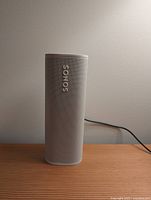 Front view of white Sonos Roam speaker powered, logo visible