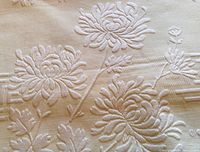 Close-up of raised chrysanthemum motif on yellow matelassé fabric