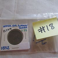 Photo of 1852 Upper Canada half penny token in white cardboard holder marked B234 C33 and dated 1852.