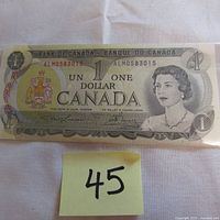 Front side of the 1973 Canadian one dollar banknote showing Queen Elizabeth II with serial number ALM0583015 and Canadian coat of arms.