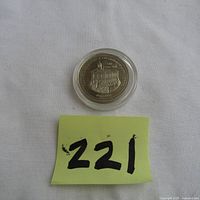 Full view of the trade dollar coin in protective casing with lot number 221