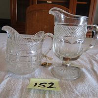 Two antique glass creamers, smaller on the left, larger on right, showing overall size and patterns