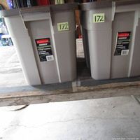Two large Rubbermaid Roughneck plastic storage bins placed side by side showing the front label and condition.