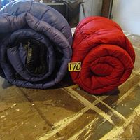 Photo of the two sleeping bags rolled up, showing blue and red colors, labels visible
