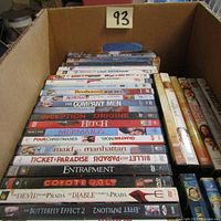 Box of DVD movies showing titles and cases stacked vertically in cardboard box