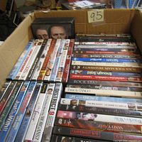 Top view showing two rows of DVD movies in a cardboard box with a label "95" on the side with assorted movie titles visible.