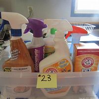 Plastic bin containing 8 unopened household cleaning products, visible spray bottles and baking soda box