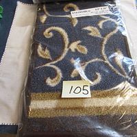 Photo of packaged navy and beige stair mats showing decorative pattern and size sticker 8.5" x 26".