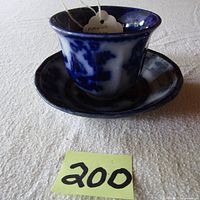 Photo showing the flow blue handleless octagonal cup and saucer from an angled perspective highlighting color and shape.