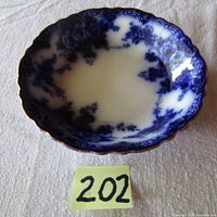 Top view of the Antique Meakin Flow Blue plate showing the blue floral pattern and gold scalloped edge.