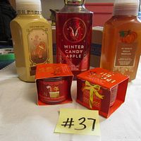 Photo showing three Bath and Body Works products: 2 bottles of foaming hand soap with gingerbread and pumpkin pecan waffles scents, and one bottle of Winter Candy Apple shower gel. Also shows two small boxed single wick candles in holiday packaging.