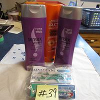 Photo of two purple Sunsilk shampoo bottles, an orange Garnier Fructis shampoo bottle, and Sensodyne toothpaste with toothbrushes in front.