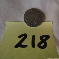 Photo of coin with number tag 218 under it for auction lot identification.