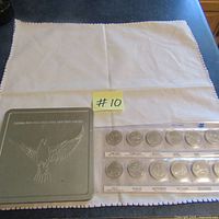 Full shot of the set laid out on white cloth showing metal tin and coins in strip labeled by month