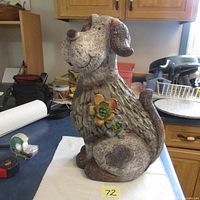 Full side view of the ceramic dog figurine showing textured surface and flower detail on chest.
