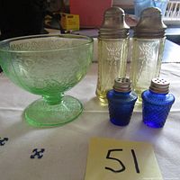 Full lot view showing green ice cream dish, amber Federal Madrid salt and pepper shakers, and small blue cobalt shakers all on white cloth with lot number card.