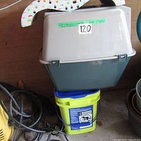 Covered cat litter box with new scoop and half-full cat litter bucket beneath it