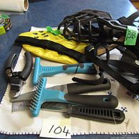 Photo of various dog grooming tools including combs, rakes, nail clippers, yellow glove, and black dog muzzle with straps.