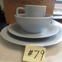 Stacked set of light blue dinnerware including plates, a bowl, and a cup with handle