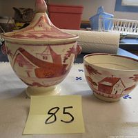Photo showing the sugar bowl with lid and the matching cup set on a cloth, displaying their scenic rural village designs and lion handles on sugar bowl sides.
