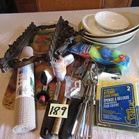 Photo showing multiple kitchen miscellaneous items including two large glass cutting boards with fruit and vegetable designs, a lint roller, several kitchen utensils, brushes, cleaning sponges, and small packaging containing mounts and a replacement microwave dish.