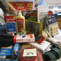 Overview photo showing assorted unopened adhesive products, repair mortar packet, mounting tape, white mounting squares, and black electrical wire.