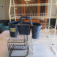 Six organizational items grouped showing white metal shoe rack, black compartmentalized caddy, black corner plate holder, white wire spice rack, and two black metal cupboard stands on a table
