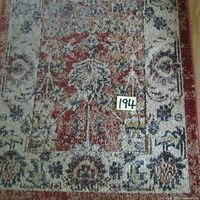 Close-up of multicolor floral and geometric design on the rug's border with a '194' tag visible, showing the woven texture and color detail.