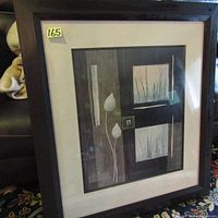 Framed artwork featuring abstract botanical design with brown/black frame, beige mat, glass faced