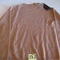 Front view of the beige/light brown cashmere sweater laid flat showing overall condition and size tag attached.