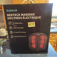 Front of unopened product box showing Nekteck foot massager with heating, massage heads and nodes info.