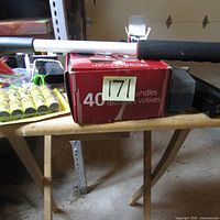 Close-up of the box of 40 votive candles on the wooden TV tray showing label and surrounding items like tape rolls and packing tape tool.