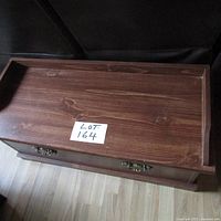 Top view of the wooden storage chest showing its wooden grain surface and label with lot number.