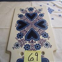 Top side view of the rectangular ceramic cheese board with decorative blue and purple heart and floral motifs.