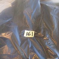 Photo of the garment laid out or packaged, dark material visible.