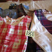 Photo showing five layered jumpers and sweatshirt, visible Oshkosh cherry print jumper and some other jumpers underneath including brown corduroy and plaid ones.