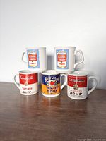 Five collectible Campbell's soup mugs arranged in a group showing front labels.