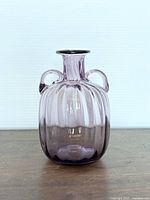 Front view of a purple amethyst fluted glass vase with two small curved handles and flared neck.