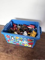 Blue Lego Duplo bin filled with numerous toy cars and vehicles seen from a top angle.