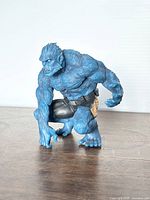 Front and side view showing muscular details, crouching pose, blue fur texture, black shorts with yellow accents and intense facial expression