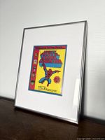 Full view of the framed booklet, showing silver frame and white matting.