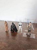 Four Star Wars figurine ornaments of Chewbacca, Darth Vader, Stormtrooper, and Rey standing in a row on a flat surface with white background