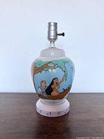 Photo of lamp front side showing Pocahontas and John Smith sitting on a tree branch with blue sky background.