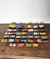Full view of all 33 vintage diecast toy cars arranged on a wooden surface.
