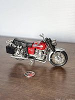 Front side view of the red and silver Moto Guzzi V7 diecast motorcycle model with black saddlebags and original round stand.