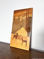 Full view of the rectangular wood inlay artwork showing the deer and forest scene with trees and foliage.