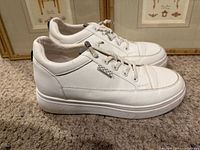 Left side view of both sneakers showing leather uppers and sole