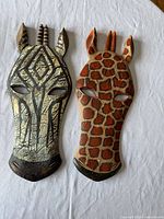 Front view of zebra and giraffe wooden wall masks on white background