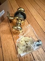Complete Schlage polished brass door knob set with hardware bag on wood floor