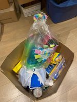 Full box containing multiple bags and containers of colorful plastic party cups, plates, and cutlery.